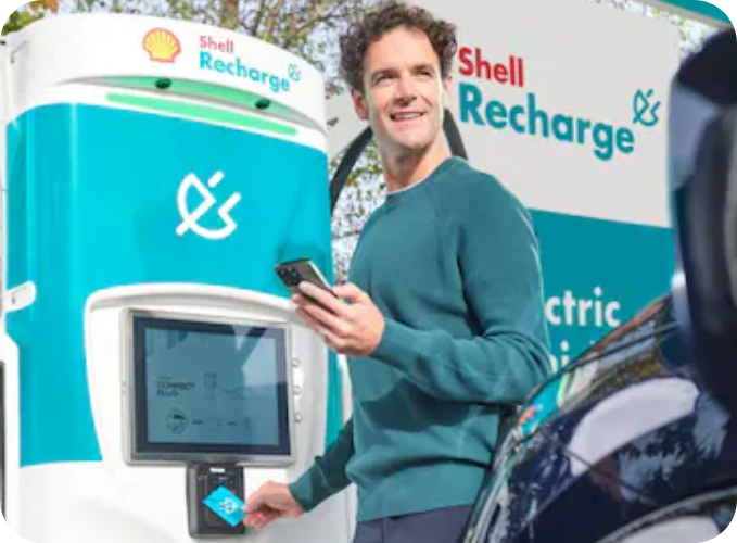 Driver using a Shell Recharge rapid EV charging station with a 50kW charger for convenient public electric vehicle charging.