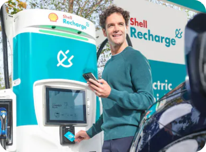 Customer using a Shell Recharge electric vehicle charging station with a smartphone and EV charge card at an ultra-rapid public EV charger.