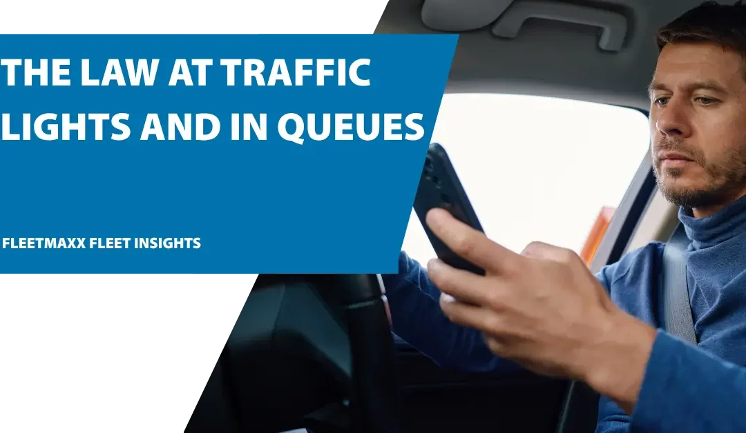 Driver using a mobile phone while stopped in traffic, highlighting UK mobile phone driving laws.