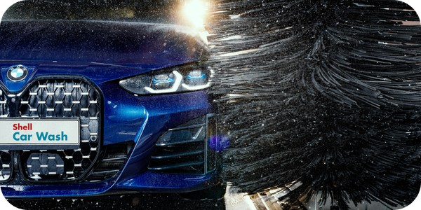 Blue company car being cleaned by an automatic Shell Car Wash, available to eligible Fleetmaxx Shell Card customers.