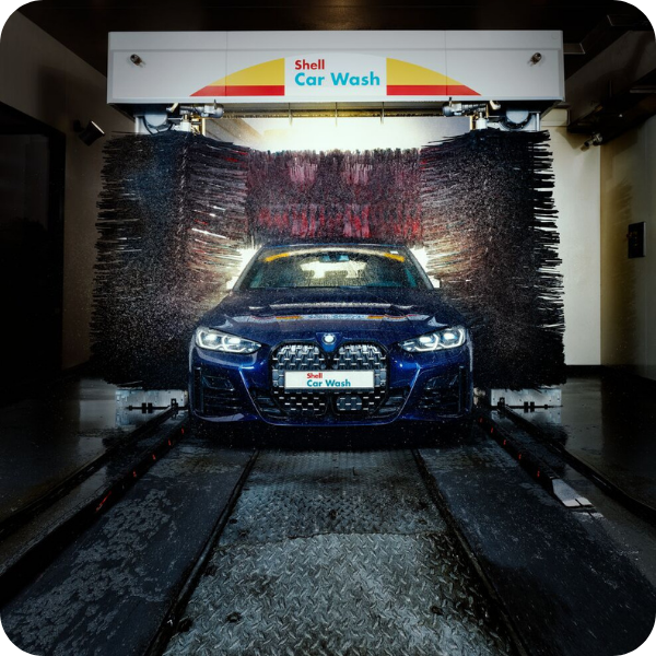Blue company car being cleaned in an automatic Shell Car Wash, which eligible drivers can pay for using a Fleetmaxx Shell Card.
