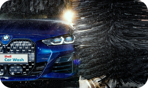 Blue company car being cleaned by automatic brushes at a Shell Car Wash available to eligible Shell Fuel Card customers.